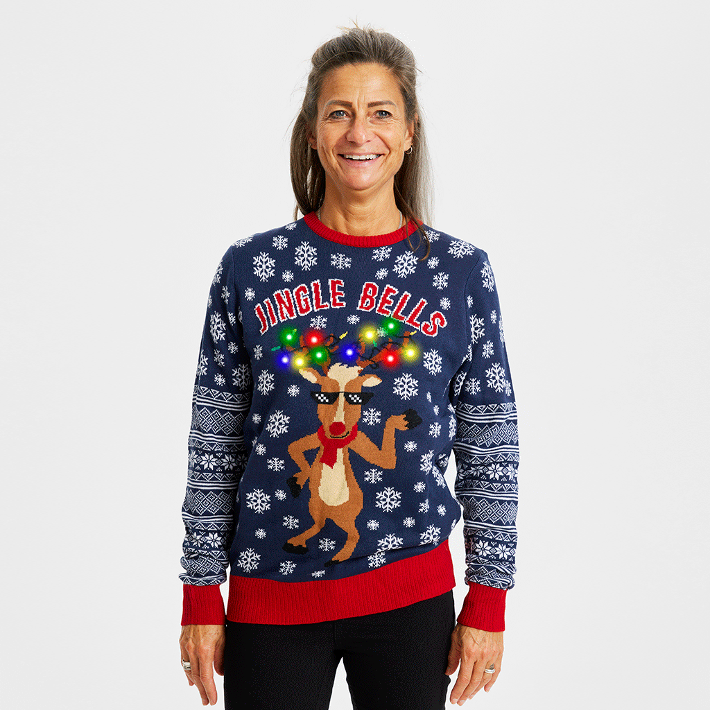 Una donna in posa che indossa un maglione natalizio blu con una renna danzante.